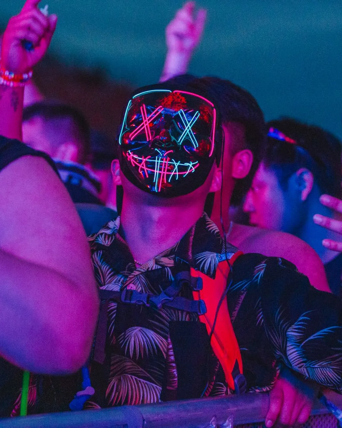 Friends at the front of a rave, lit in neon